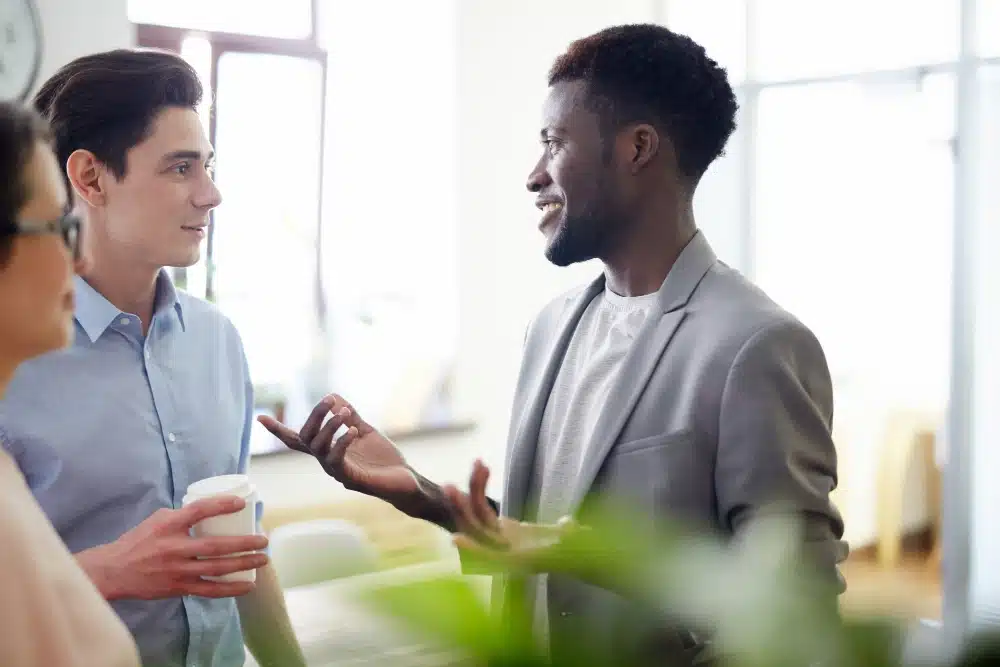 Homem e mulher em uma conversa de trabalho colaborativa em frente a um notebook, ilustrando a parceria entre agência e cliente para entender o que fazer quando se reclama dos leads.